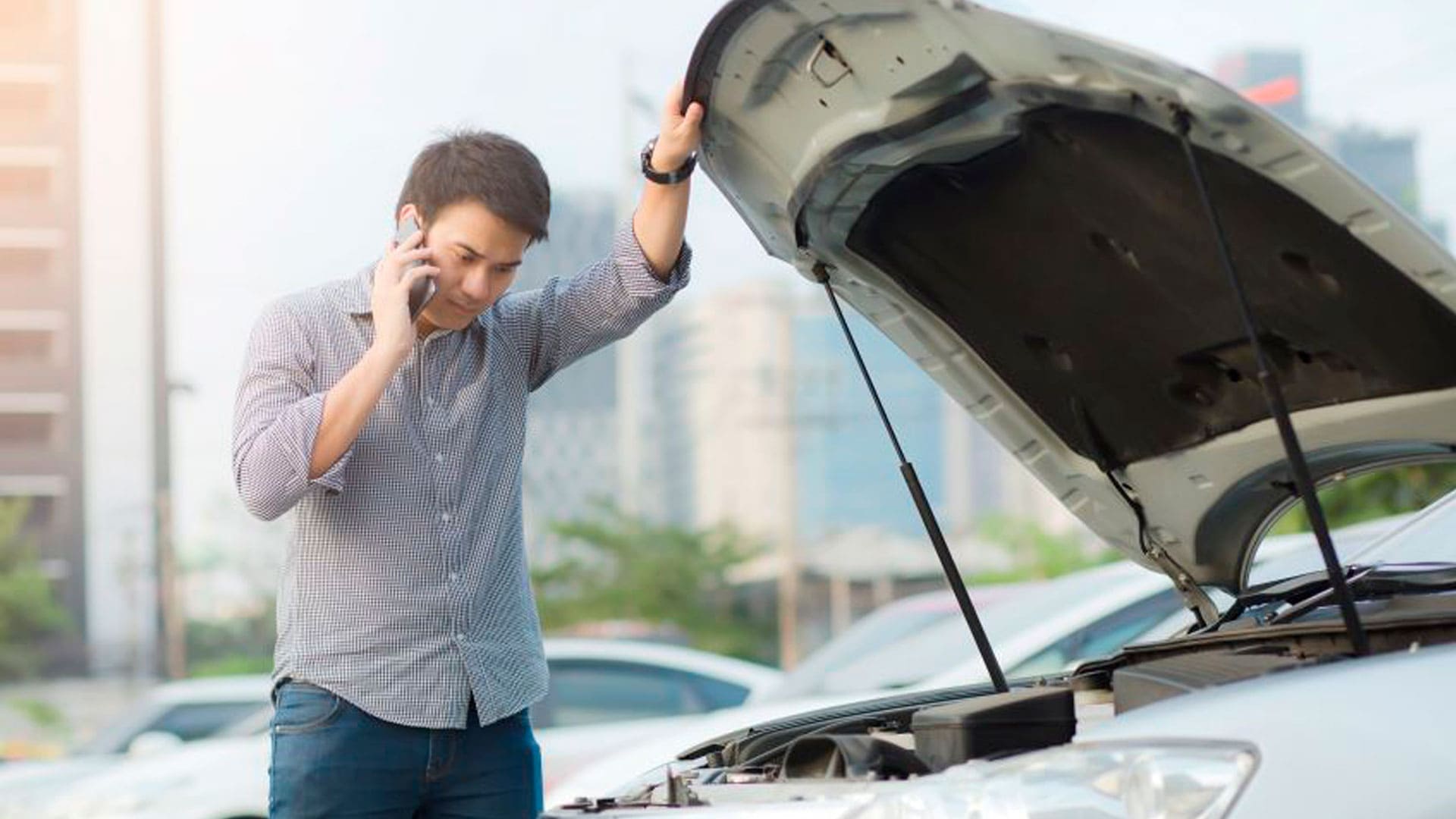 Conductor con el coche detenido en el arcén tras quedarse sin batería mientras espera asistencia en carretera.